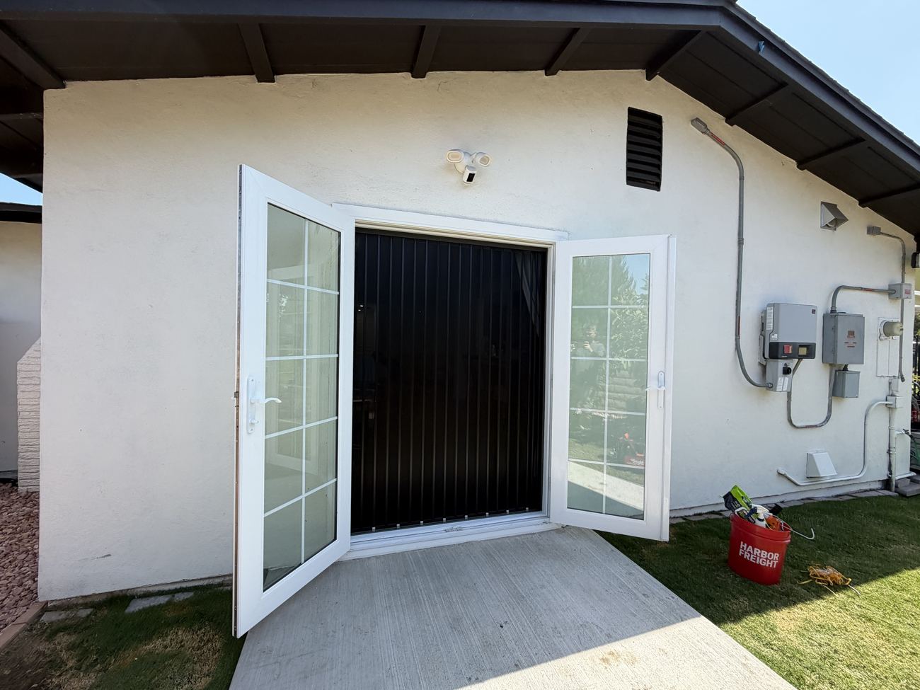 Black folding screen behind two open white French doors