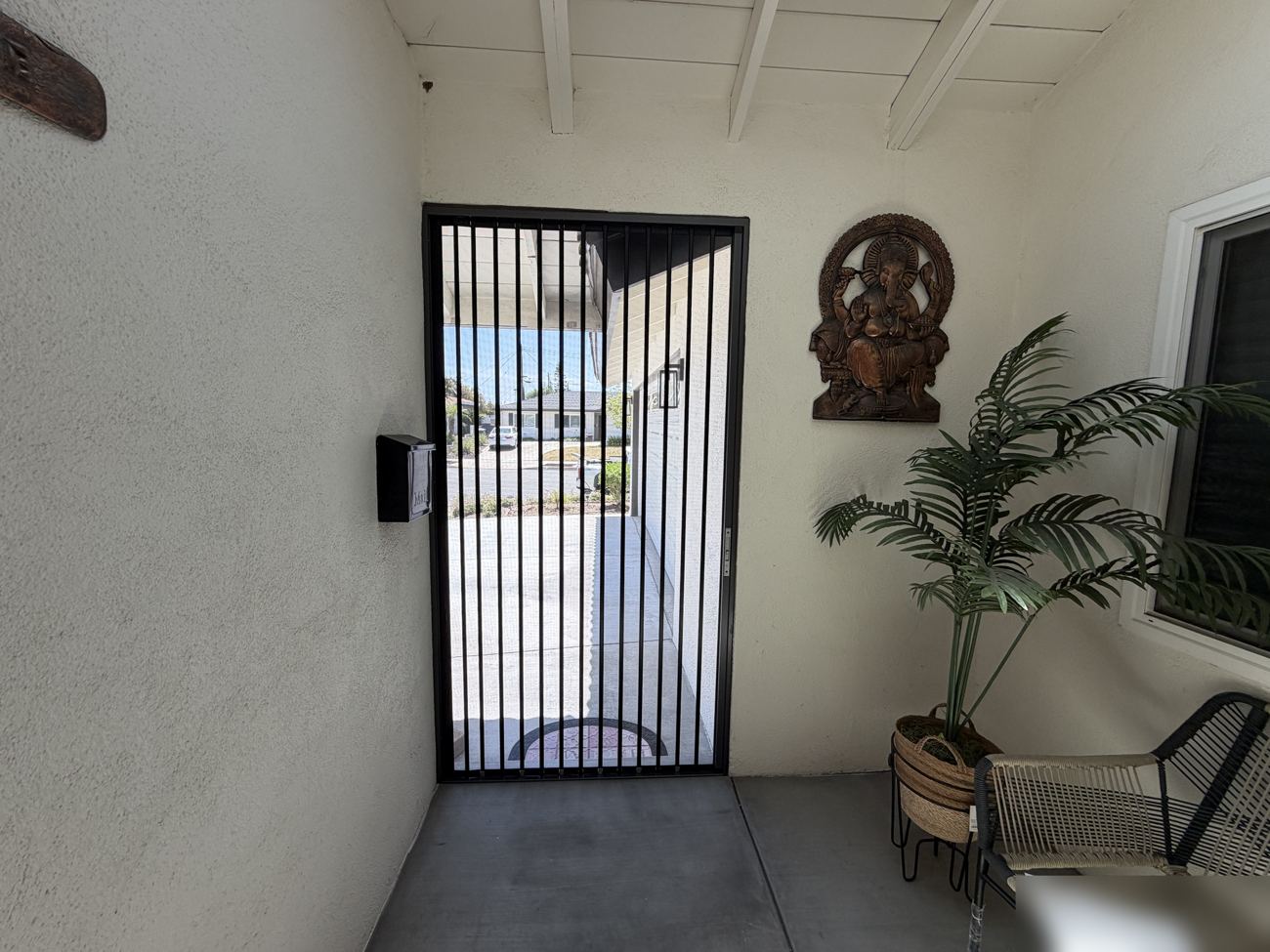 View from inside through a black folding screen to the driveway and street