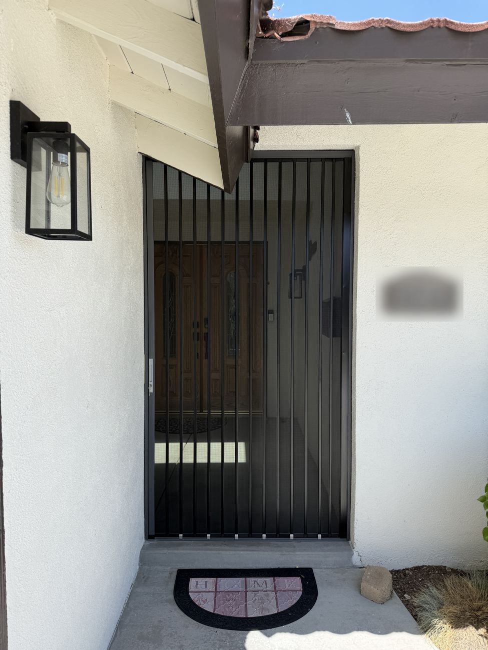 Black folding screen across a double front door under a covered porch