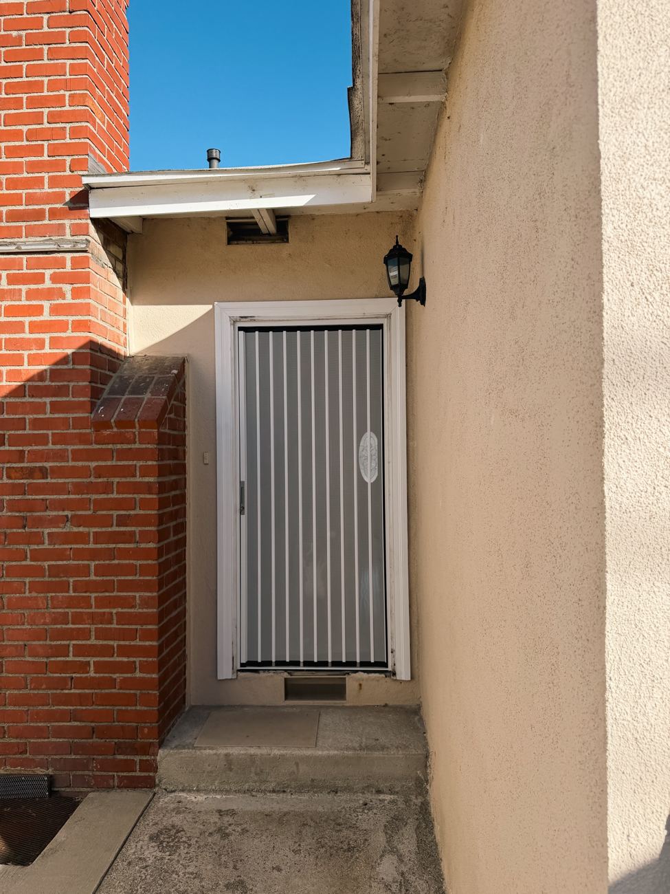 White folding screen on a side door beside a brick chimney