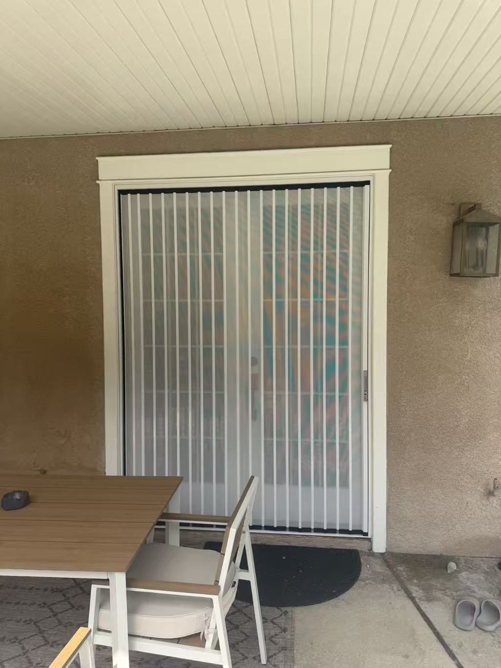White folding screen across a pair of French doors on a covered patio