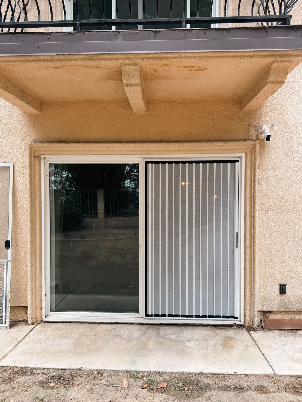 White folding screen in one panel of a sliding patio door under a balcony