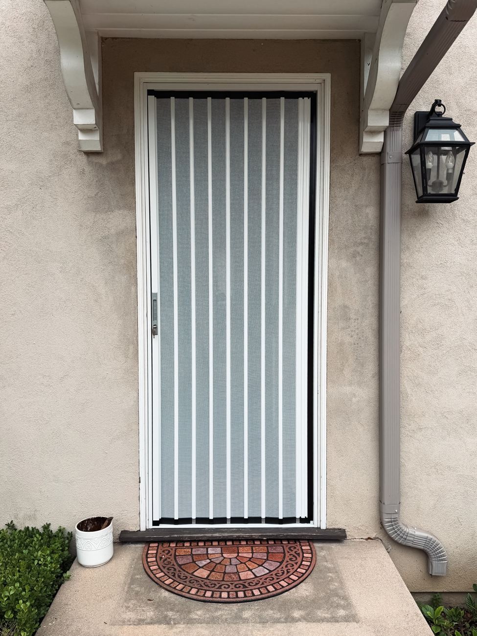 White folding screen on a single door under a bracketed porch roof
