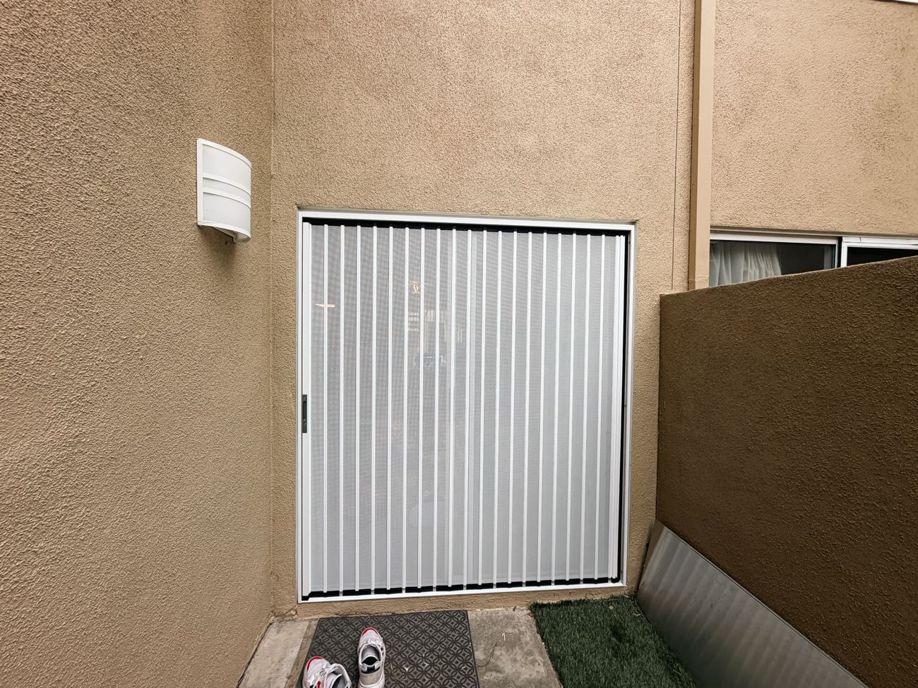 White folding screen filling a square opening in a stucco wall