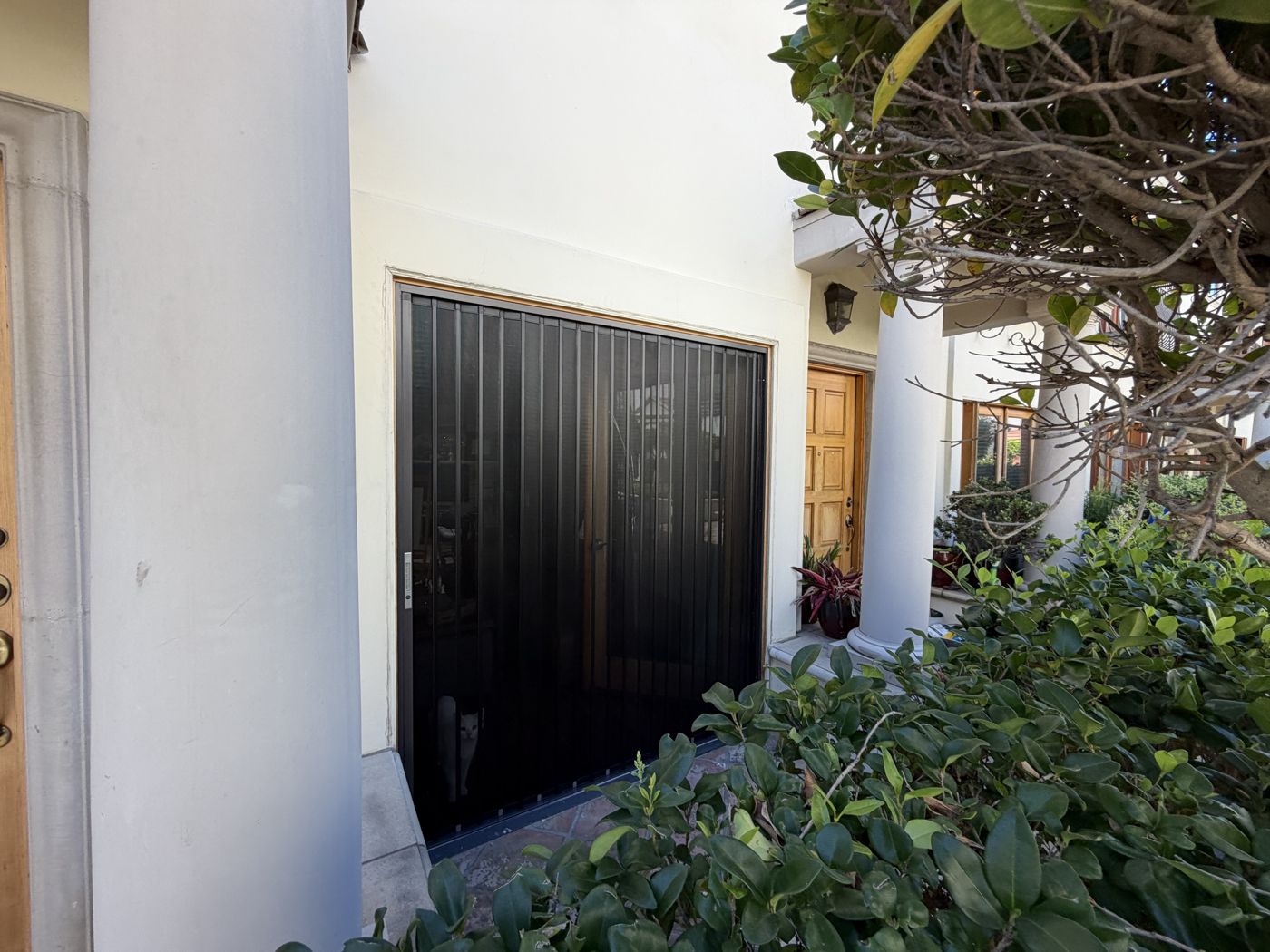 Wide black folding screen filling a large opening beside a wood door