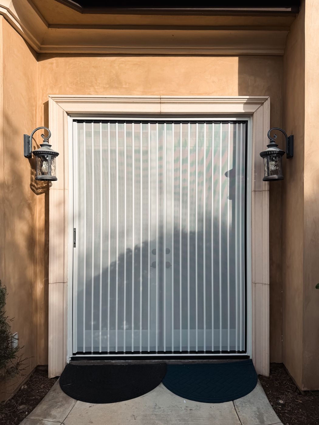 White folding screen closed across a wide stucco double door with lanterns