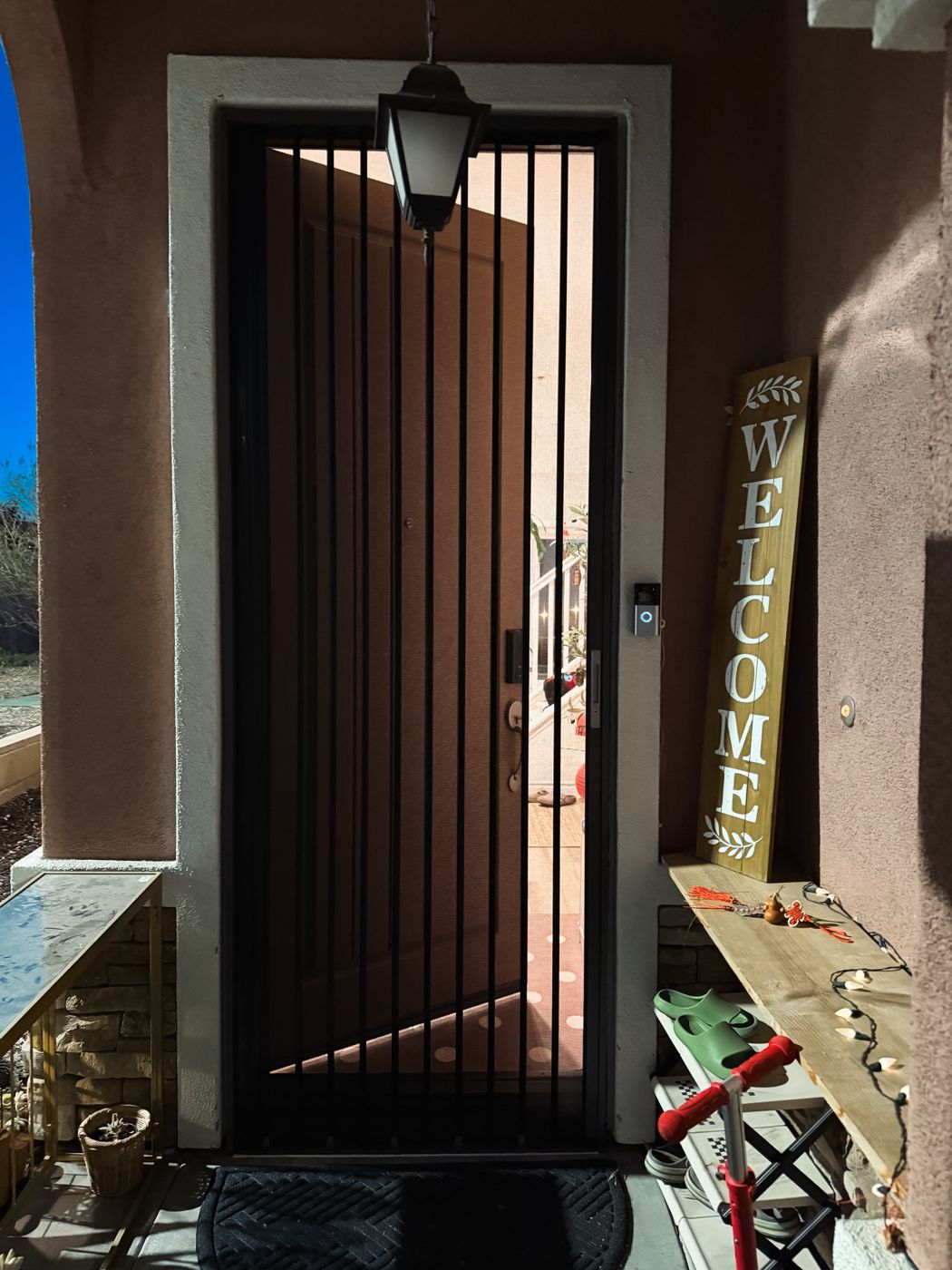 Black folding screen on a front door with a welcome sign beside it